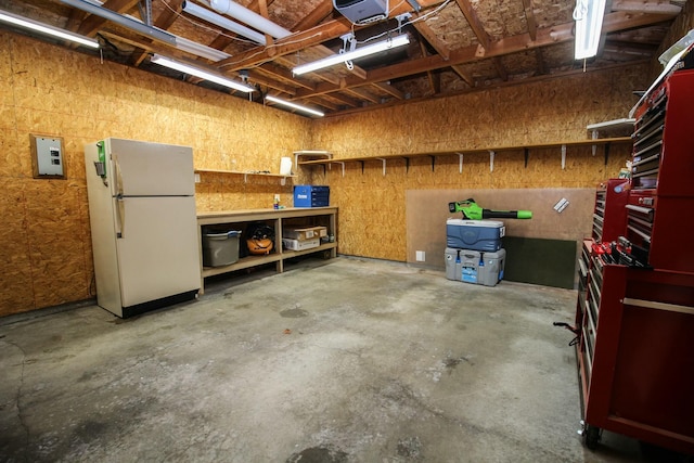 interior space with a garage door opener, a workshop area, and freestanding refrigerator