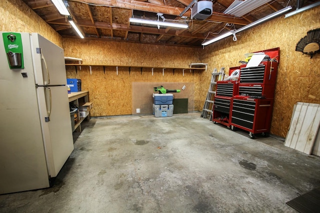 garage featuring a garage door opener, a workshop area, and freestanding refrigerator