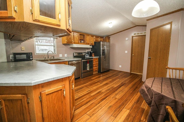 kitchen featuring brown cabinets, light countertops, appliances with stainless steel finishes, glass insert cabinets, and a sink