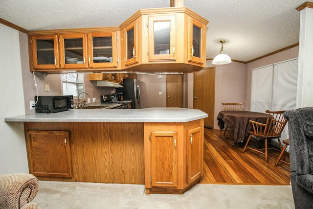 kitchen with black microwave, a sink, light countertops, brown cabinets, and glass insert cabinets