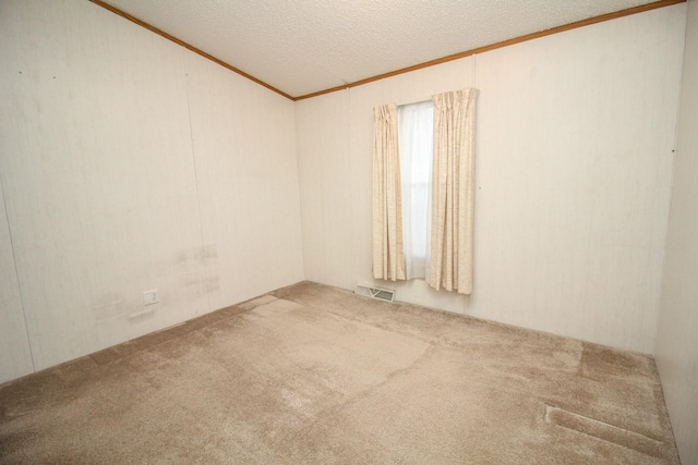 carpeted spare room with a textured ceiling, visible vents, and crown molding