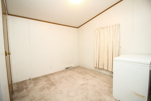 spare room with visible vents, crown molding, light carpet, and a textured ceiling