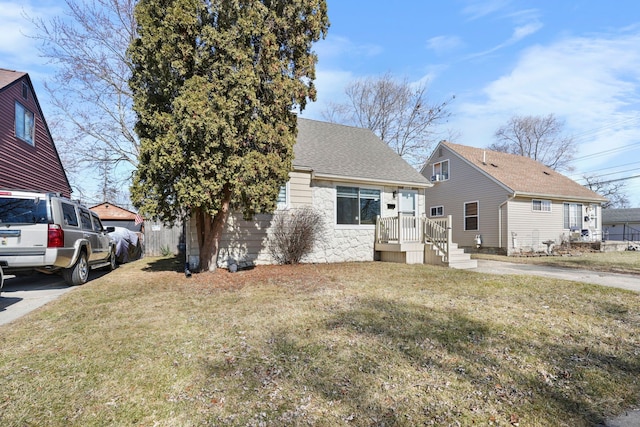 view of front facade featuring roof with shingles and a front lawn