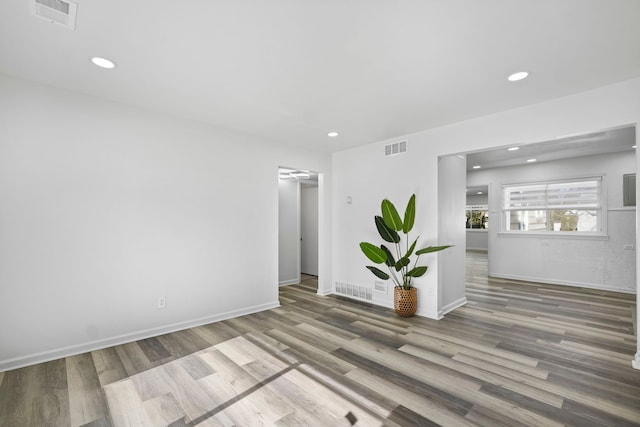 empty room with baseboards, visible vents, wood finished floors, and recessed lighting