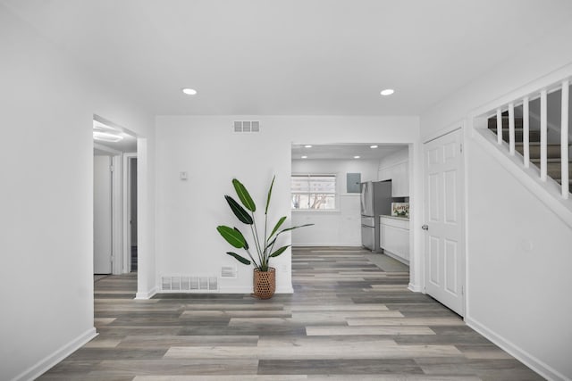 corridor with stairs, wood finished floors, visible vents, and recessed lighting