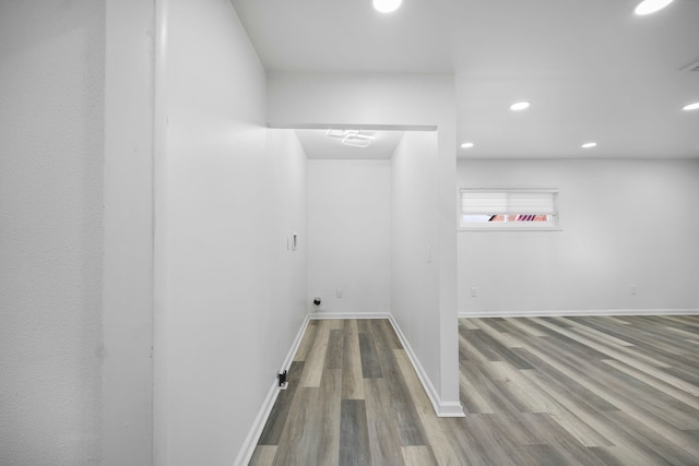 clothes washing area featuring baseboards, wood finished floors, and recessed lighting