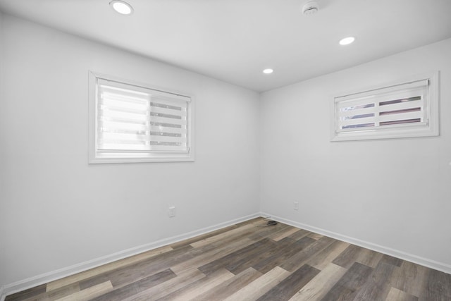 spare room with baseboards, wood finished floors, and recessed lighting