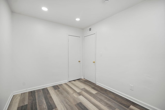 spare room with baseboards, visible vents, wood finished floors, and recessed lighting