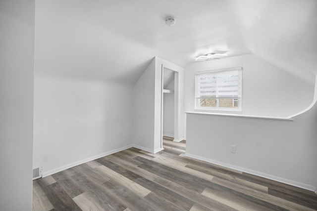 additional living space featuring vaulted ceiling, wood finished floors, visible vents, and baseboards