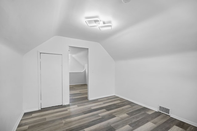 additional living space featuring visible vents, vaulted ceiling, baseboards, and wood finished floors