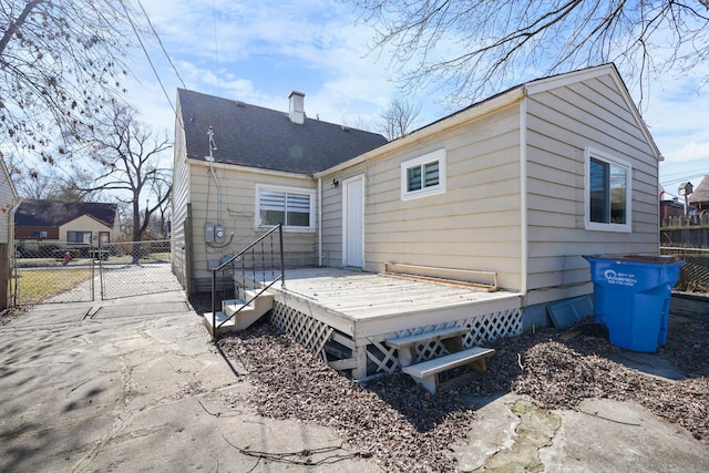 back of property with a shingled roof, a chimney, a gate, fence, and a deck