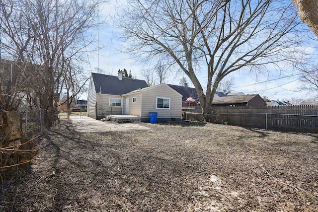 back of house with a chimney, fence, and a wooden deck