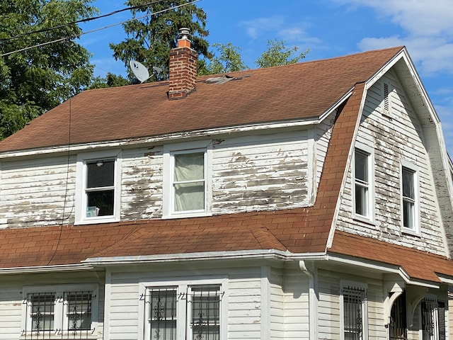 view of property exterior with roof with shingles, a chimney, and a gambrel roof