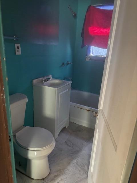 bathroom with a tub to relax in, marble finish floor, toilet, and a sink