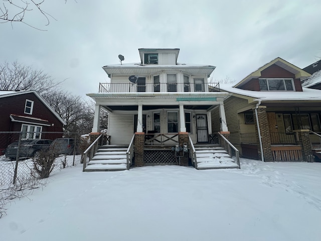 american foursquare style home featuring a porch and a balcony