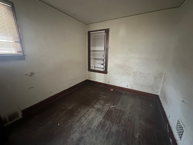 spare room featuring dark wood-style floors, visible vents, and baseboards