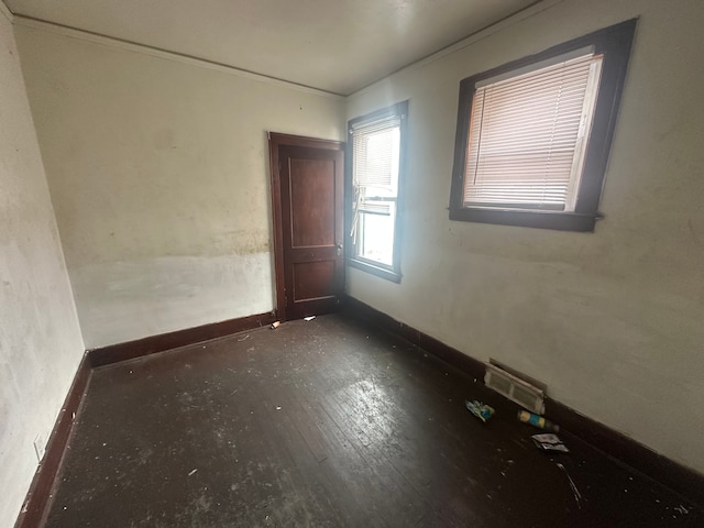 unfurnished room with dark wood-style floors, visible vents, and baseboards