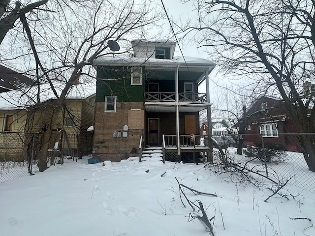 view of front of home with a balcony, fence, a porch, and brick siding