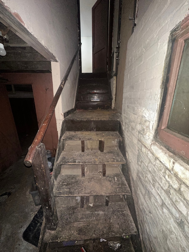 staircase featuring brick wall