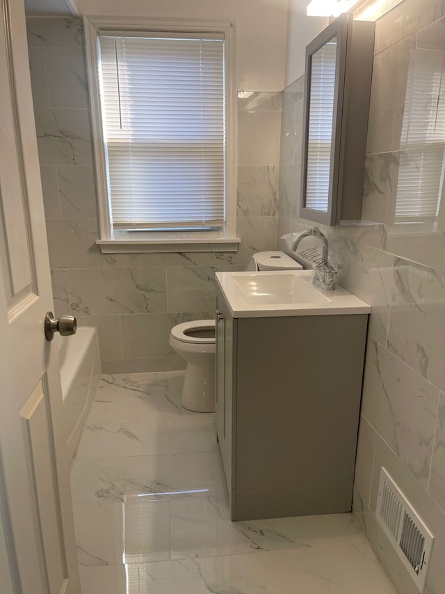 bathroom featuring marble finish floor, vanity, visible vents, and tile walls