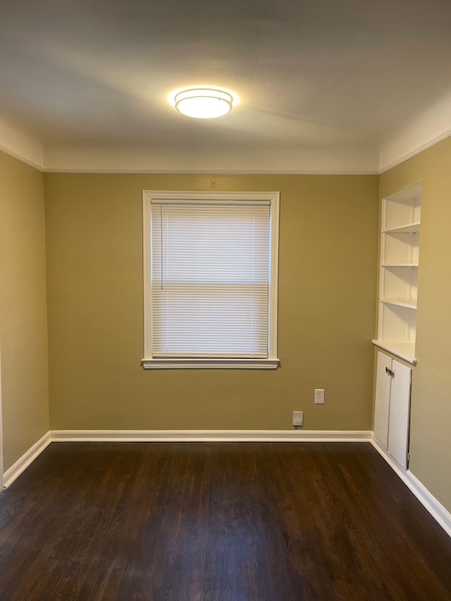 unfurnished room featuring crown molding, baseboards, and dark wood-type flooring