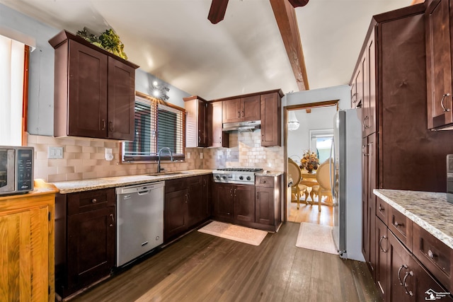 kitchen with light stone counters, dark wood-type flooring, stainless steel appliances, under cabinet range hood, and a sink