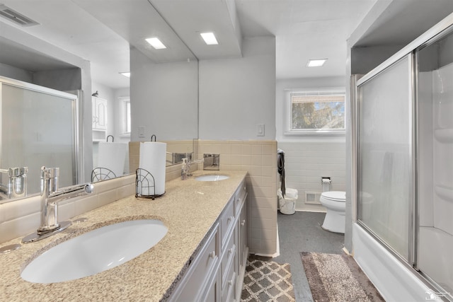 full bathroom featuring toilet, a sink, visible vents, and tile walls