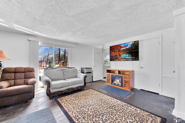 living room with a glass covered fireplace, concrete floors, and a textured ceiling