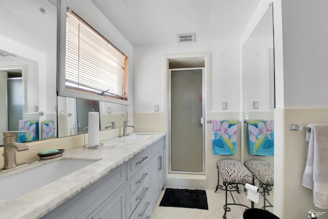 bathroom with a stall shower, a sink, and visible vents