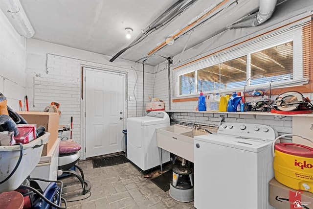 washroom featuring laundry area, brick wall, a sink, and independent washer and dryer