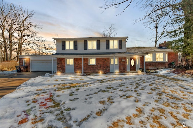 traditional-style house with a garage, brick siding, driveway, and a chimney