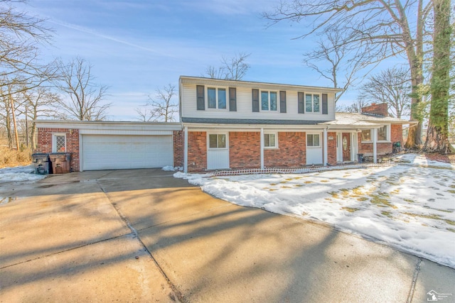 traditional-style home with brick siding, driveway, a chimney, and an attached garage