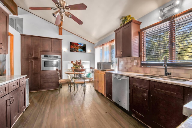 kitchen featuring decorative backsplash, lofted ceiling, appliances with stainless steel finishes, dark wood-style flooring, and a sink