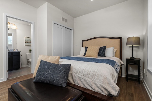 bedroom with a closet, visible vents, connected bathroom, wood finished floors, and baseboards