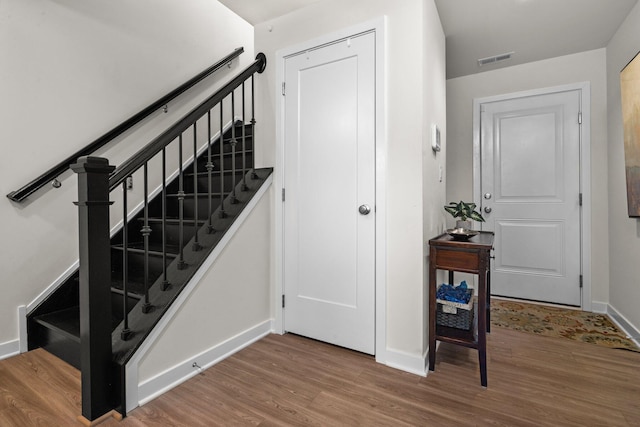 staircase with baseboards, visible vents, and wood finished floors