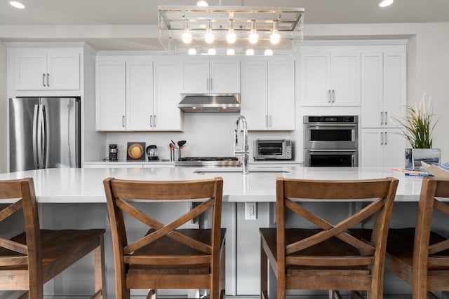 kitchen with stainless steel appliances, white cabinets, light countertops, and under cabinet range hood