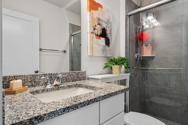 bathroom with a shower stall, toilet, and vanity