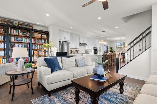 living room with recessed lighting, baseboards, stairway, dark wood-style flooring, and ceiling fan with notable chandelier