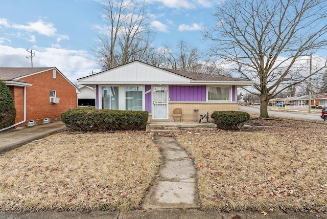 bungalow-style home with cooling unit, covered porch, and brick siding