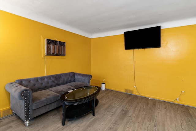 living room featuring baseboards, visible vents, wood finished floors, and a wall mounted air conditioner