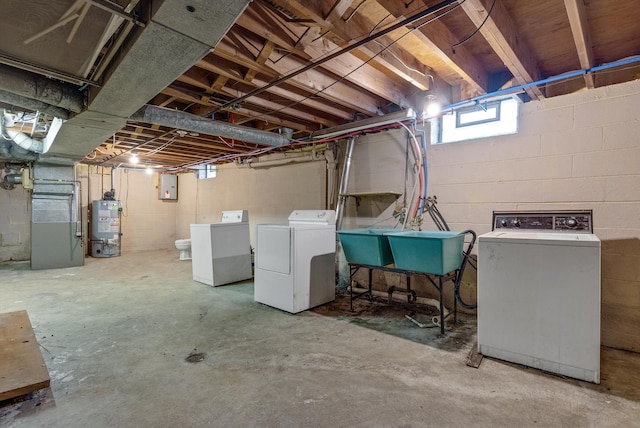 basement with electric panel, heating unit, washer and dryer, water heater, and a sink