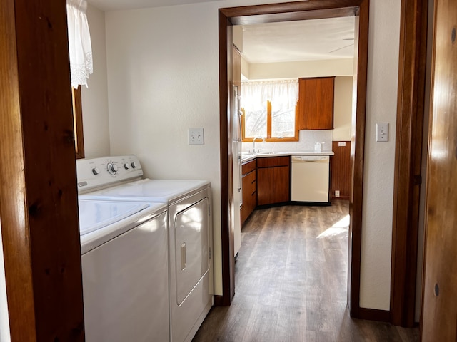 laundry room featuring dark wood-type flooring, washing machine and dryer, a sink, laundry area, and baseboards