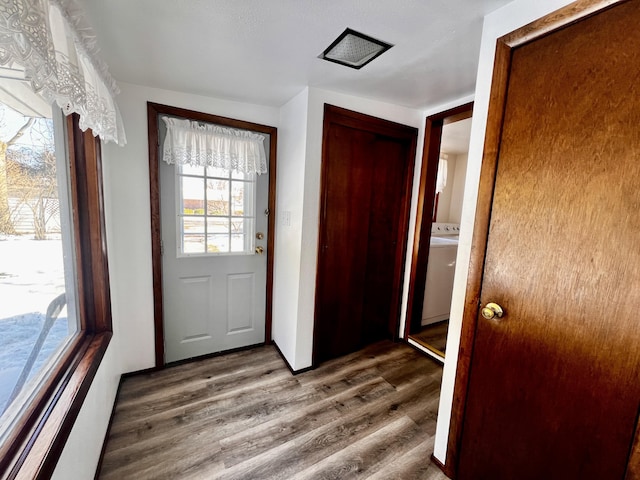 doorway to outside with washer / clothes dryer and wood finished floors