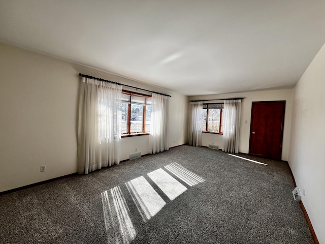 unfurnished room with baseboards, visible vents, and dark carpet