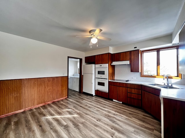 kitchen with white appliances, independent washer and dryer, light countertops, under cabinet range hood, and a sink