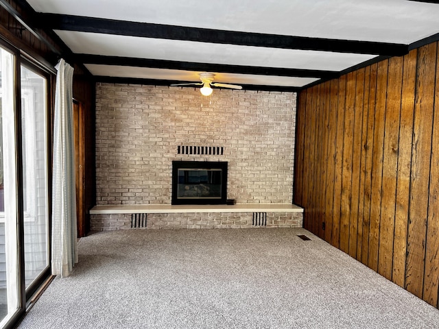 unfurnished living room featuring wood walls, carpet, and a brick fireplace