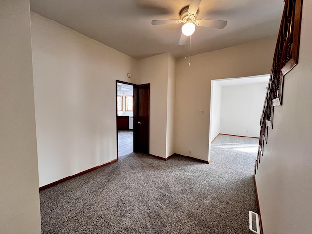 carpeted empty room featuring a ceiling fan, visible vents, and baseboards