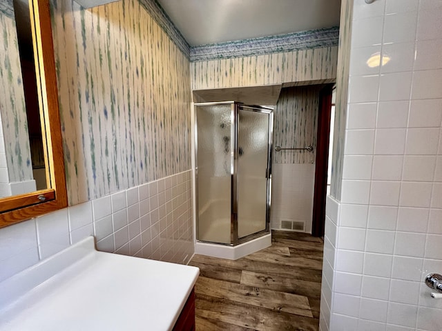 full bath featuring visible vents, vanity, tile walls, a shower stall, and wallpapered walls