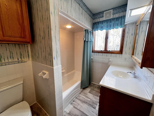 full bath with shower / bath combo with shower curtain, tile walls, and wallpapered walls