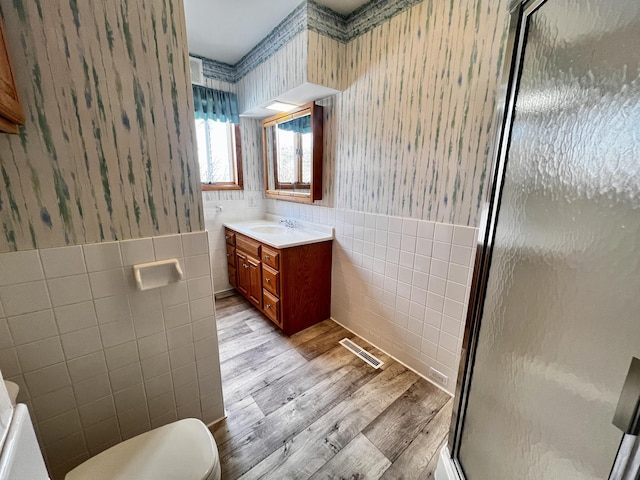 bathroom with visible vents, vanity, tile walls, a stall shower, and wallpapered walls